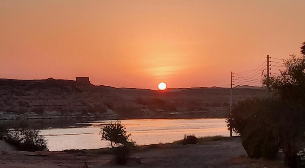 een zonsondergang boven een rivier met zonsondergang bij Nile House in Abu Simbel