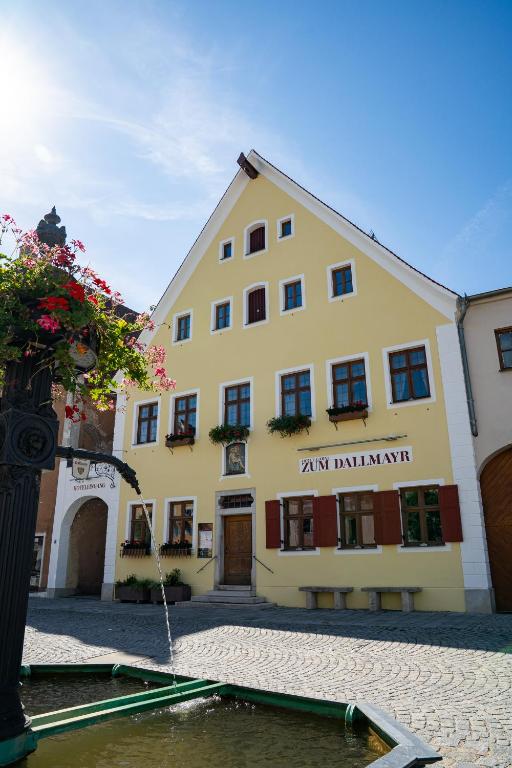 a large yellow building with a fountain in front of it at Zum Dallmayr Hotel Garni in Berching