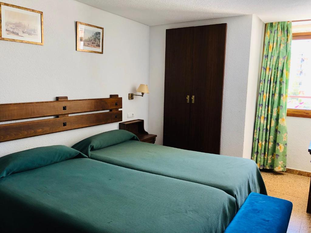 una camera con due letti verdi e una finestra di La Nogalera Experience a Torremolinos