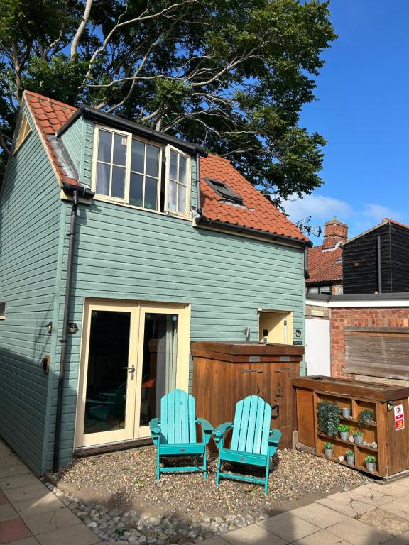 two blue chairs sitting in front of a house at Beach hut seaside cottage in Sheringham