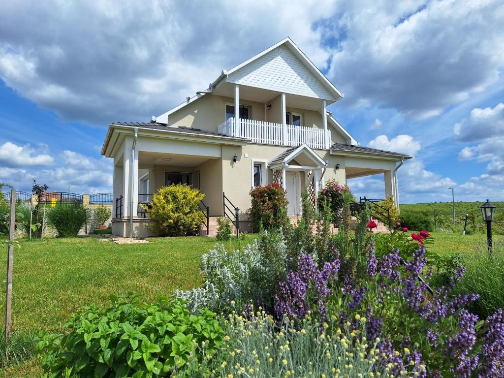a white house with flowers in the yard at Zöld Terasz Vendégház in Egerszalók