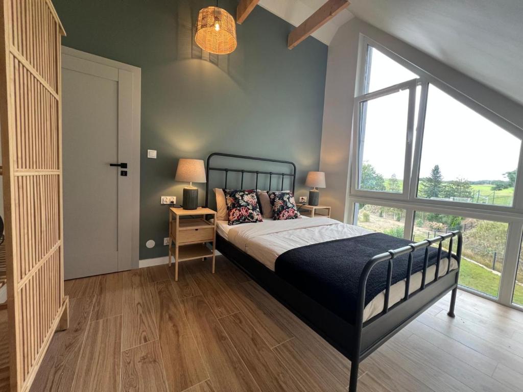 a bedroom with a bed and a large window at Villa Alcmaria - Aura Kaszub in Łączyno