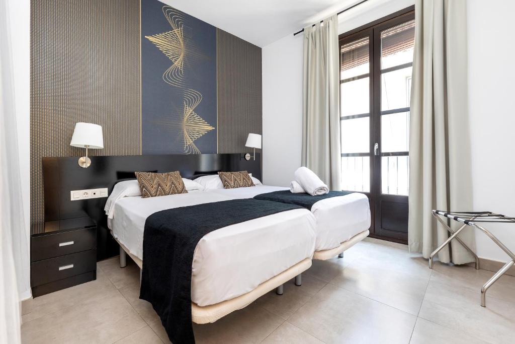 a hotel room with two beds and a window at Nest Flats Granada in Granada
