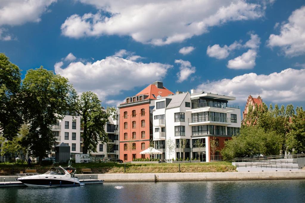 un barco en el agua frente a un edificio en HOTEL ALMOND BUSINESS & SPA BY GRANO Gdańsk, en Gdansk