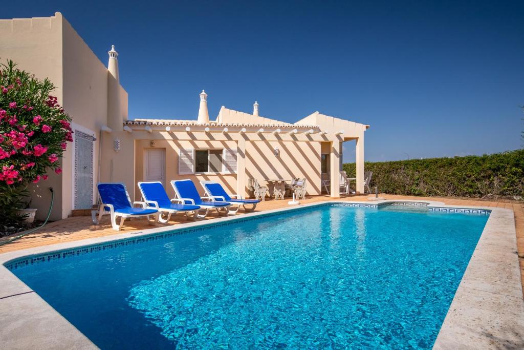 ein Pool mit blauen Stühlen und ein Haus in der Unterkunft 420 Villa Maren in Lagos