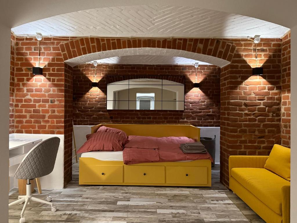 a bedroom with a yellow bed and a brick wall at Boho & Loft 2 Zimmer Parkplatz in Bad Hersfeld
