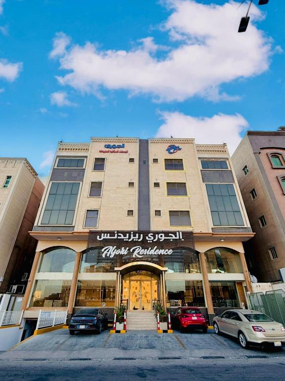 a large building with cars parked in front of it at Al Jury Serviced Apartments in Al Khobar