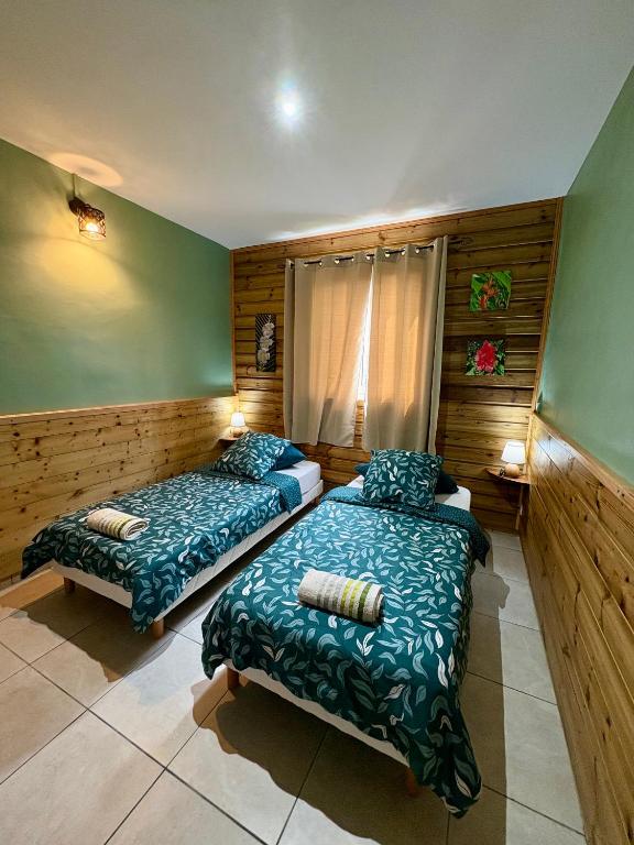 two beds in a room with wooden walls at Gite Hydrangea 974 Les chambres in La Plaine des Cafres