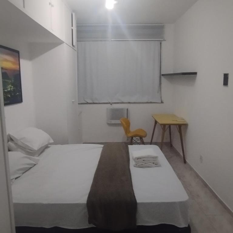 a bedroom with a white bed and a chair at Cobertura posto 5 in Rio de Janeiro