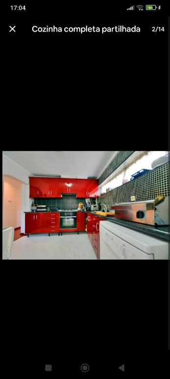 a large kitchen with red cabinets and appliances at Casa da Ruben Lisboa in Lisbon