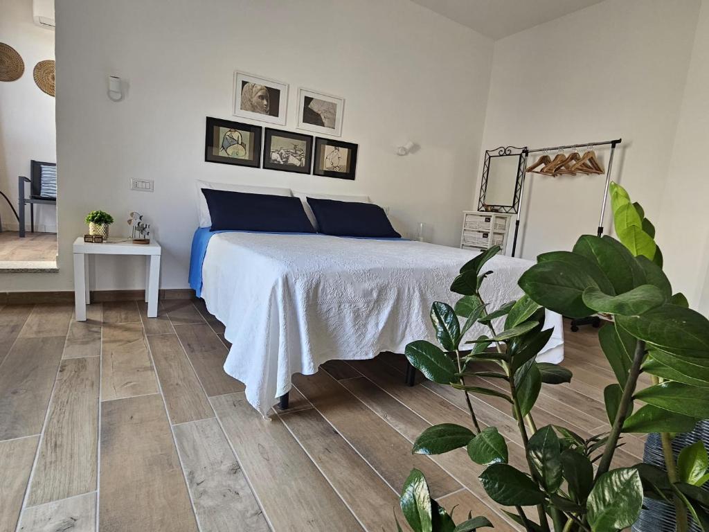 een slaapkamer met een bed met blauwe kussens en een plant bij Rose e fiori in Teulada