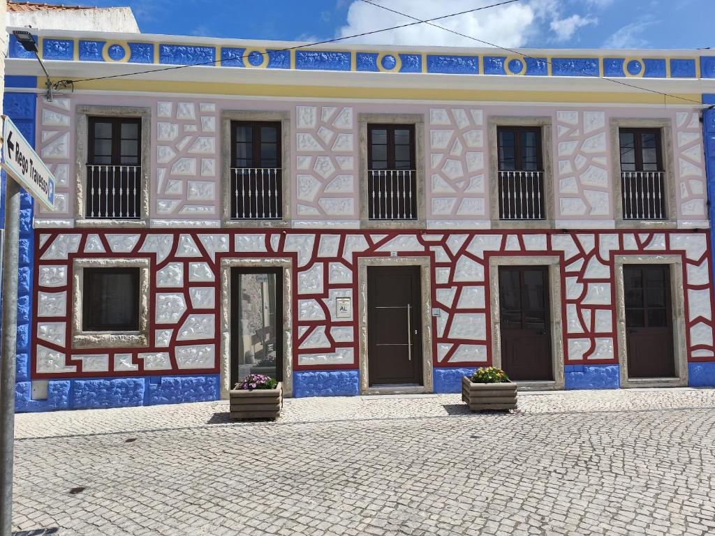 ein rosa und blaues Gebäude mit zwei Türen an einer Straße in der Unterkunft Praca e Canto in Amoreira