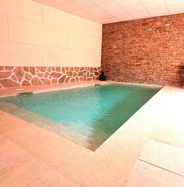 a large swimming pool with a brick wall at Casa Rural El Parque in Navalcán