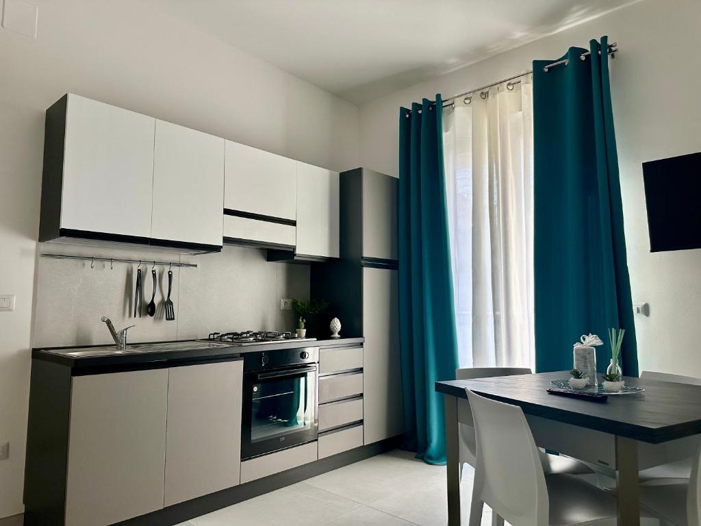 een keuken met witte kasten, een tafel en blauwe gordijnen bij Levante Casa Vacanze in Torrenova