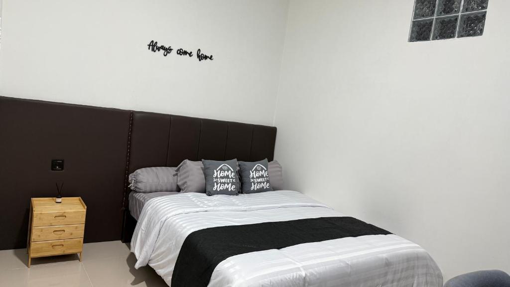 1 dormitorio con cama blanca y negra con almohadas en Kostel 77 Jepara, en Jepara