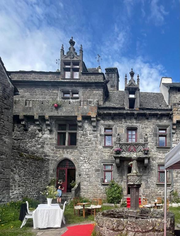 an old stone building with a table in front of it at Le Manoir des Remparts de Besse in Besse-et-Saint-Anastaise
