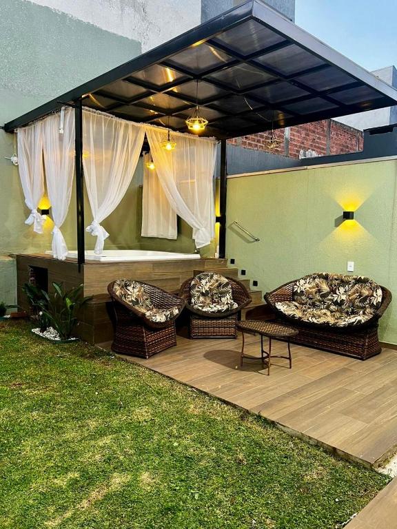 a covered patio with two chairs and a table at Casa Aconchegante Saboto in Foz do Iguaçu