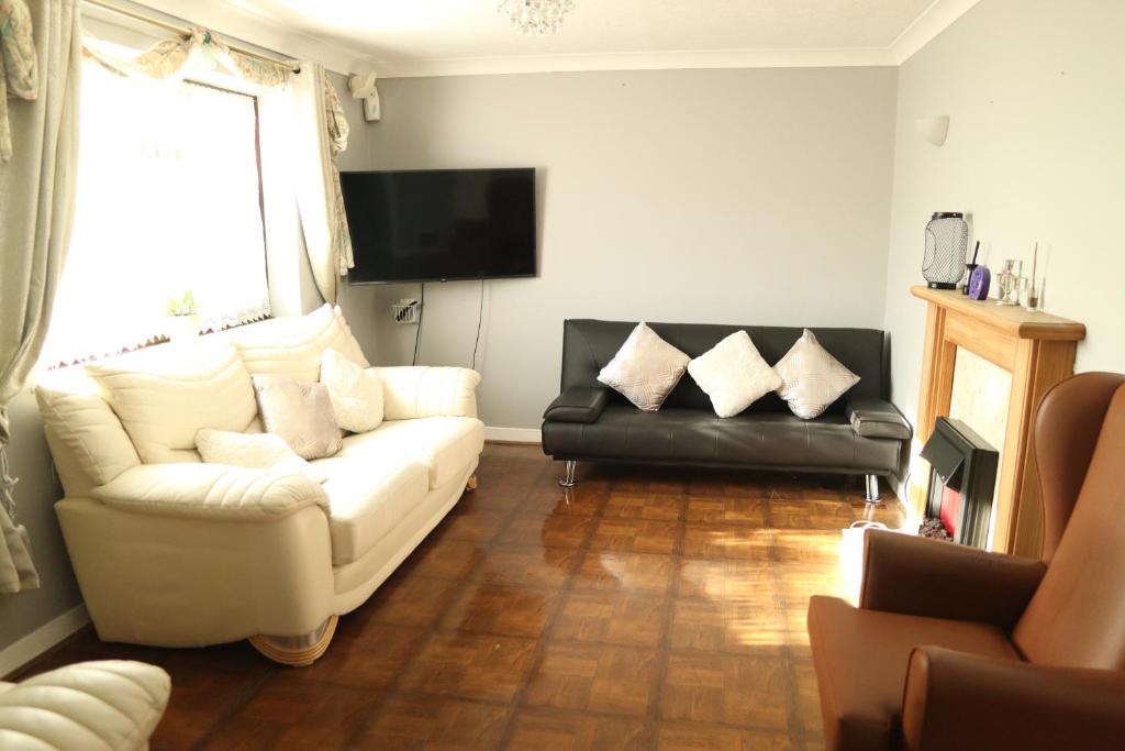 a living room with a white couch and a leather chair at Galleywood House in Great Baddow