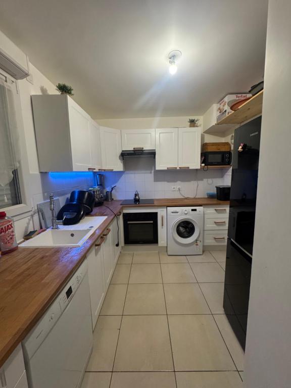a kitchen with white cabinets and a washer and dryer at La maison des vacances in Saint-Thibault-des-Vignes