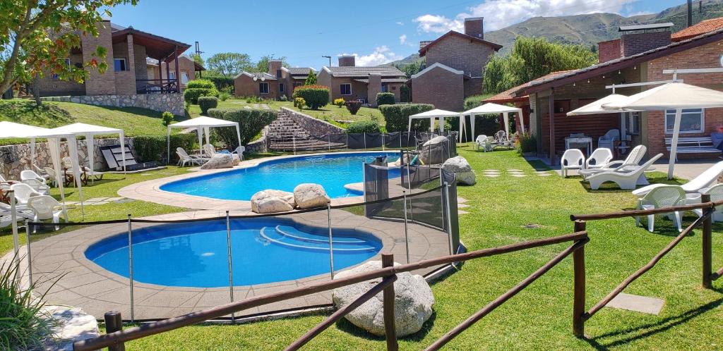 a swimming pool in a yard with chairs and a house at Vista Bella Cabañas in La Falda