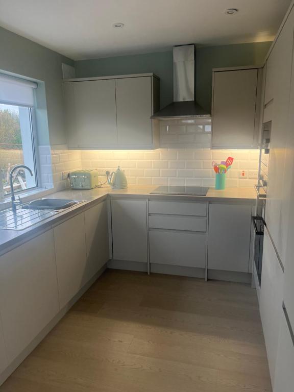 a kitchen with white cabinets and a sink and a window at MacRuairi House in Burtonport