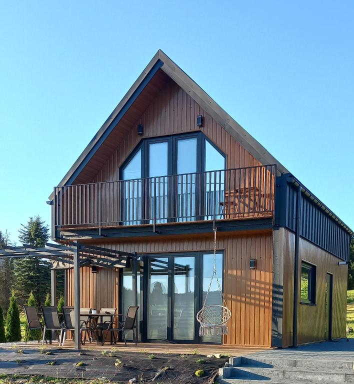 a house with a balcony and a table and chairs at Domek Noclegowy JoWish in Strachocina