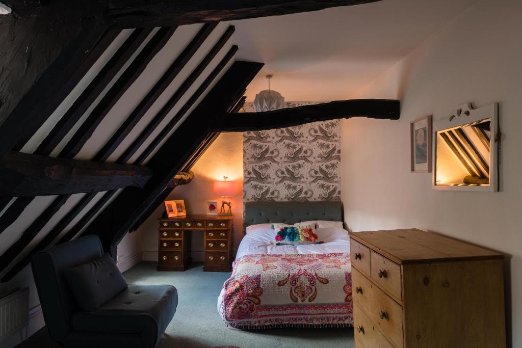 une chambre avec un lit et une chaise dans un grenier dans l'établissement The Wine Merchants House in Chipping Norton, à Chipping Norton