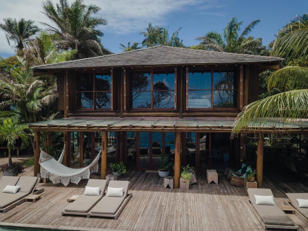 ein Haus mit einer Hängematte und Stühlen auf einer Terrasse in der Unterkunft Villa Toucan in Itacaré