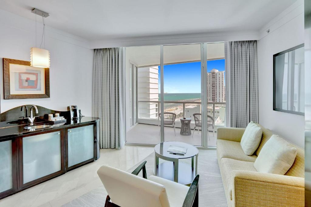 a living room with a couch and a table at Luxury Oceanview Suite at the Fontainebleau Miami Beach with Balcony, King & Sofa Bed in Miami Beach