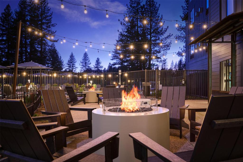 a patio with a fire pit with chairs and lights at Martis Valley Lodge, Tapestry Collection by Hilton in Truckee