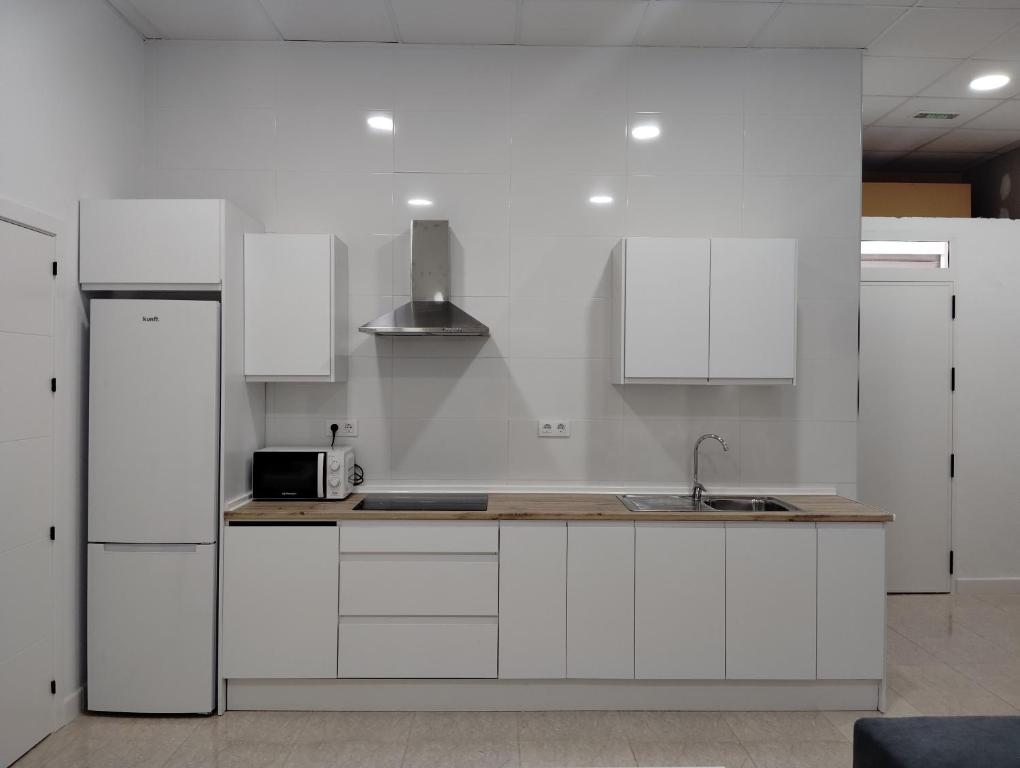 une cuisine blanche avec des armoires blanches et un évier dans l'établissement Apartamento FERIA, à Fuentes de Andalucía