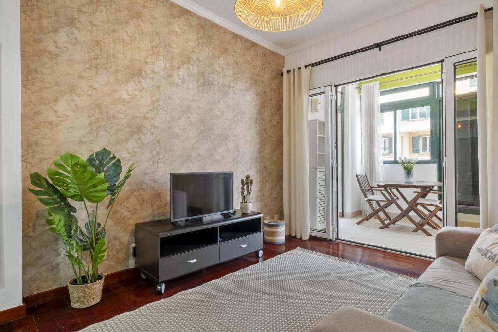 a living room with a tv and a couch at Doca's Refuge by Homie in Ilhéu do Gorgulho