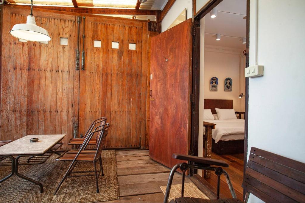 A rustic dining and work area with a table, chairs, and a bedroom beyond.