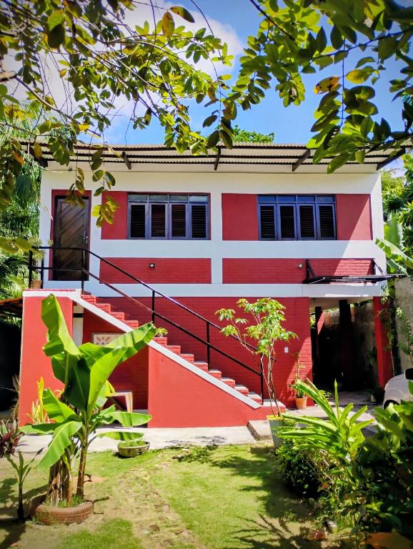 a red and white house with a yard at Hospedaria Su in Parnamirim