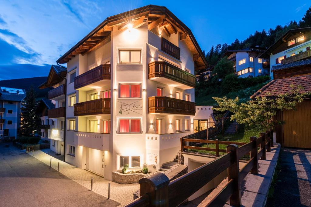 a large white building with a wooden roof at Avita - suites to relax in Ortisei