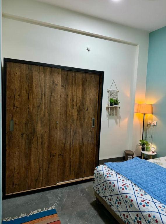a bedroom with a large wooden door next to a bed at Your Home in Indore