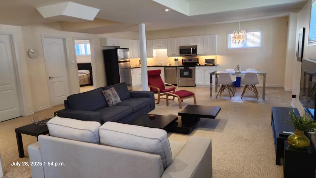 a living room with a couch and a table and a kitchen at Spacious 2 BR, 3 beds, sleeps 6, kitchen, laundry in Richmond Hill