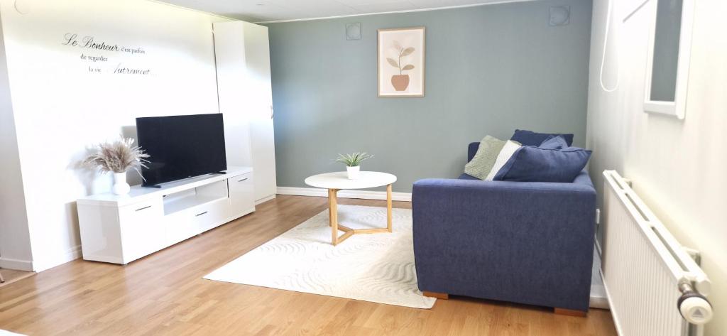 a living room with a blue couch and a tv at Calm Condo in villa area near nature in Vendelsö