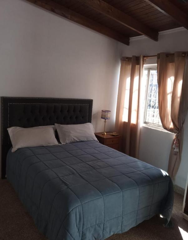 a bedroom with a bed with a blue comforter and a window at Monoambiente Blanca in Concordia