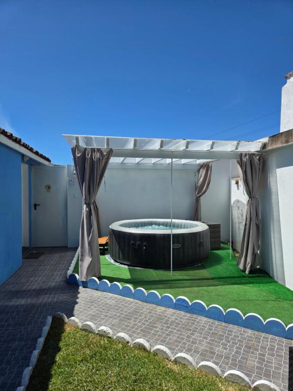 a patio with a hot tub and grass at Casa da Ermida in Ponta Delgada