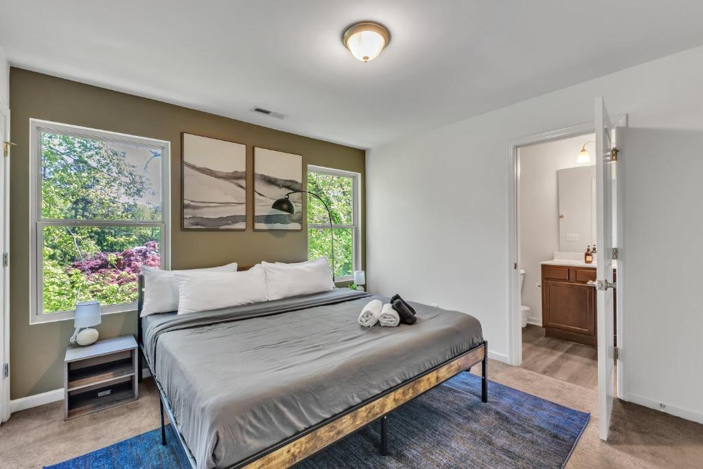 ein Schlafzimmer mit einem Bett und zwei Fenstern in der Unterkunft Upscale King 3BR Townhouse Mins to Cary & NC State in Raleigh