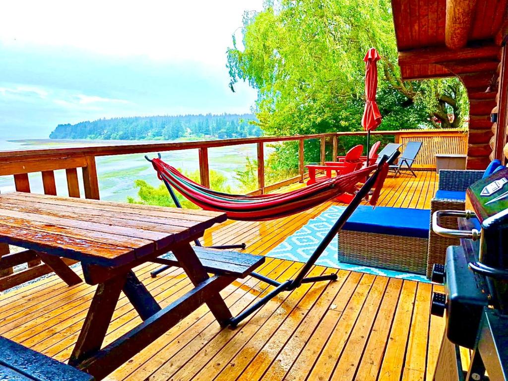 a deck with a wooden table and a hammock on it at The Beach House Texada - Gillies Bay Favourite Cabin in Gillies Bay