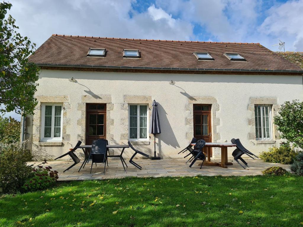 a patio with chairs and an umbrella in front of a house at Gîte familial en ferme avec jardin, proche forêt et canal d'Orléans - Label Tourisme et Handicap - FR-1-590-7 in Chailly-en-Gâtinais