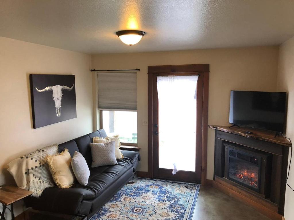 a living room with a black leather couch and a fireplace at Trail Street Condo Downstairs in Missoula