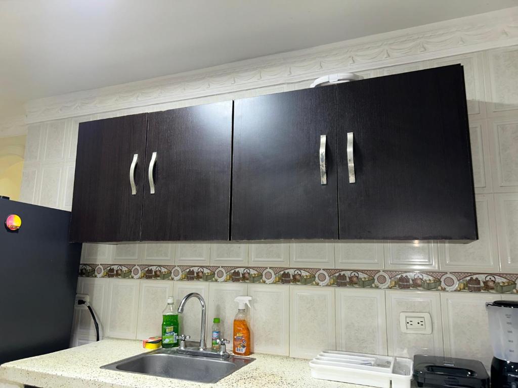 a kitchen with black cabinets and a sink at Hermoso apto piso 2 barrio san jose in Barranquilla