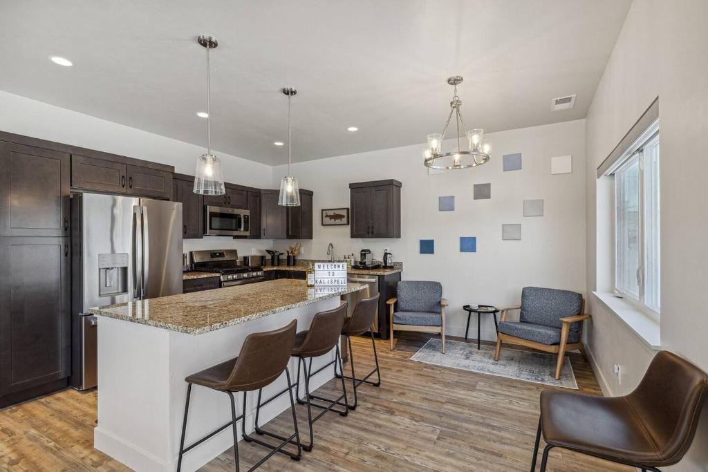 a kitchen with a bar with chairs and a counter top at My Glacier Getaway Kalispell in Kalispell