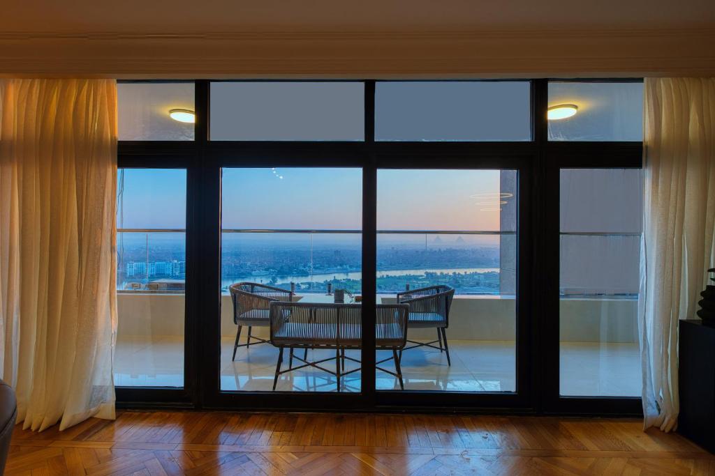 开罗Cairo Homes Maadi Nile View Family的带桌子和大窗户的餐厅