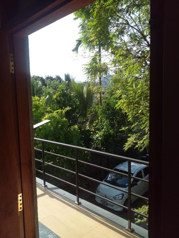 a door leading to a balcony with a car parked on a railing at Thomasha Homestay Wellawaya in Wellawaya