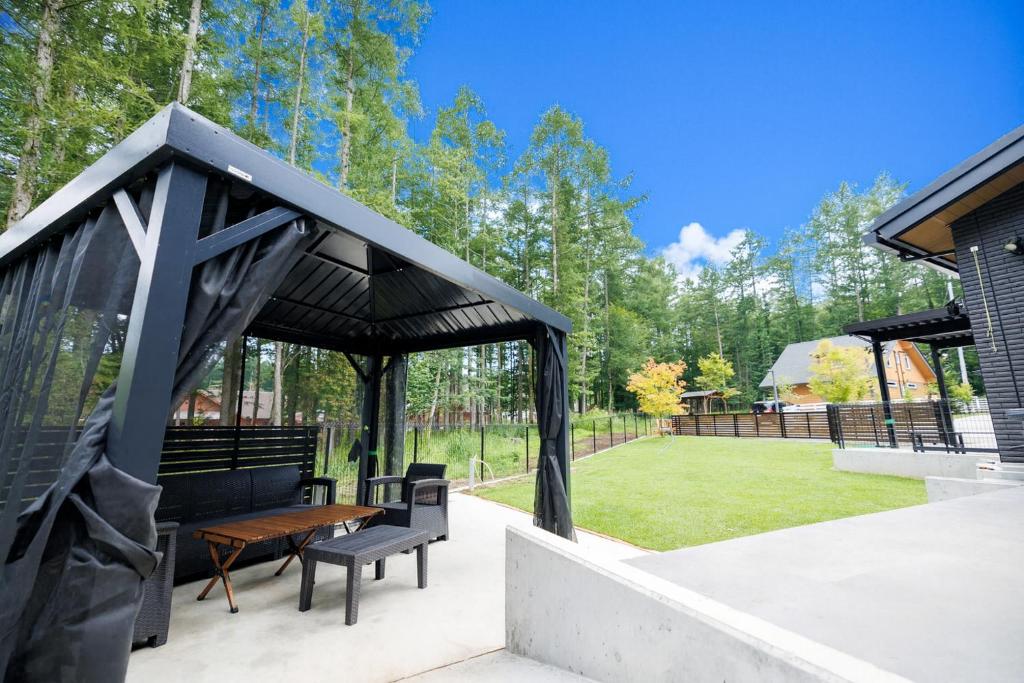 a gazebo with a wooden table and a bench at Pino-富士山麓-山中湖-新築貸切ヴィラ-蚊帳東屋BBQ無料-150平米ドッグラン付-小型犬3匹無料-長期滞在早期歓迎割引-バリアフリー in Yamanakako