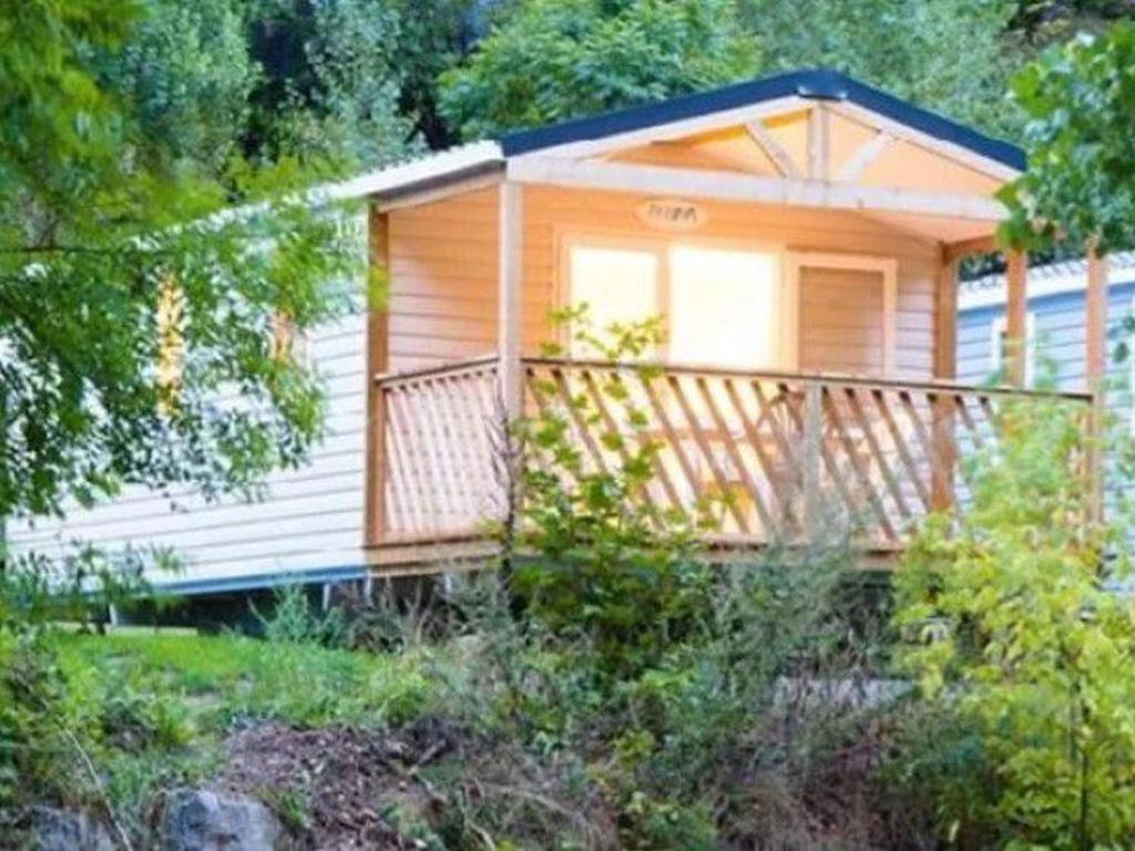 a small cabin with a large balcony in the woods at Mobil-home 4 pers avec terrasse à Meyrueis - API-1-52-432 in Meyrueis